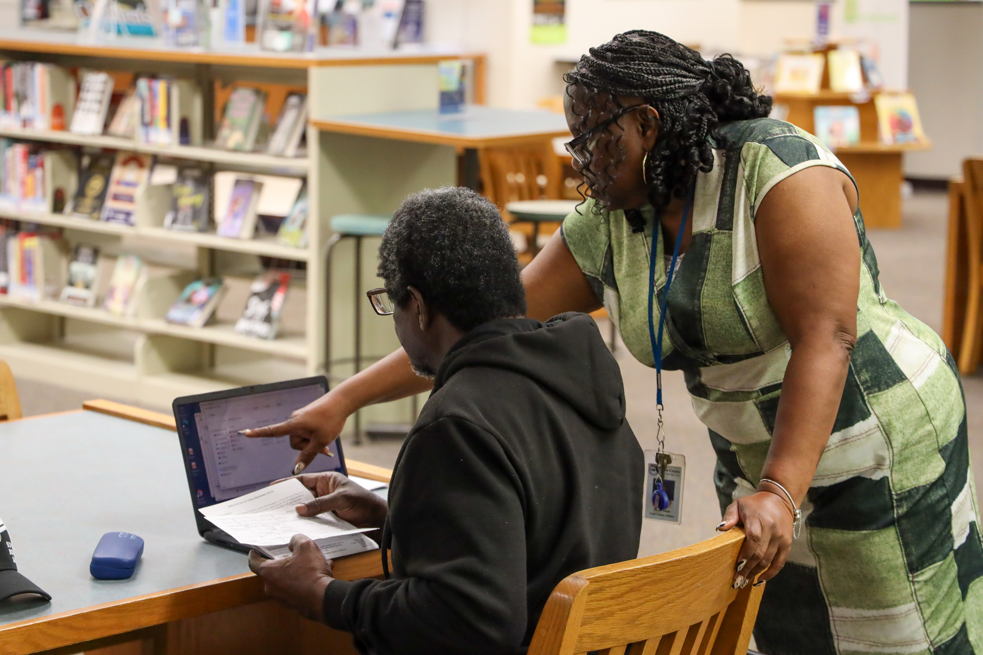 A library staff member helping a patron use the computer.